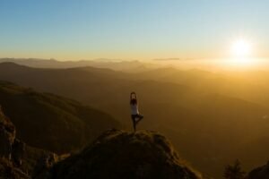 Woman stretching outdoors at sunrise on a mountain summit