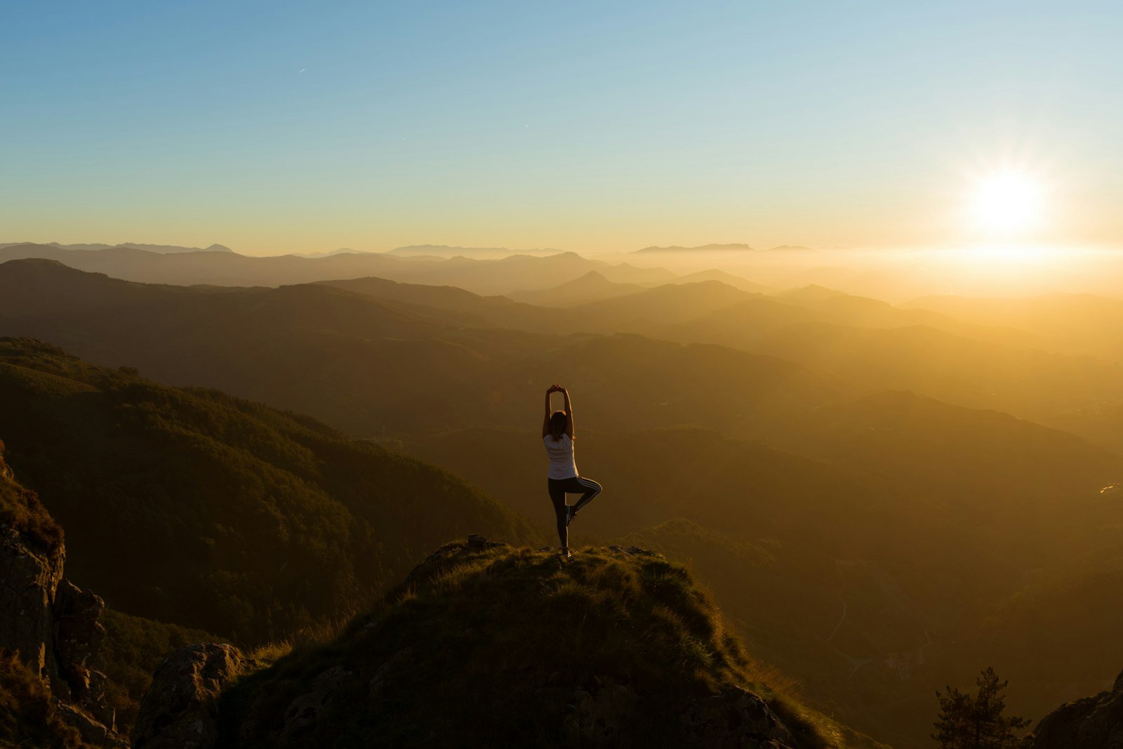 Woman stretching outdoors at sunrise on a mountain summit