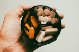 A hand holding several different supplement capsules, illustrating the choice of magnesium vs melatonin for sleep